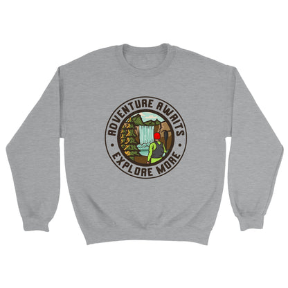 A grey crewneck sweatshirt with a round design in the centre of a kayaker looking at a waterfall he is about to run. There is text around the outside that says: adventure awaits, explore more.